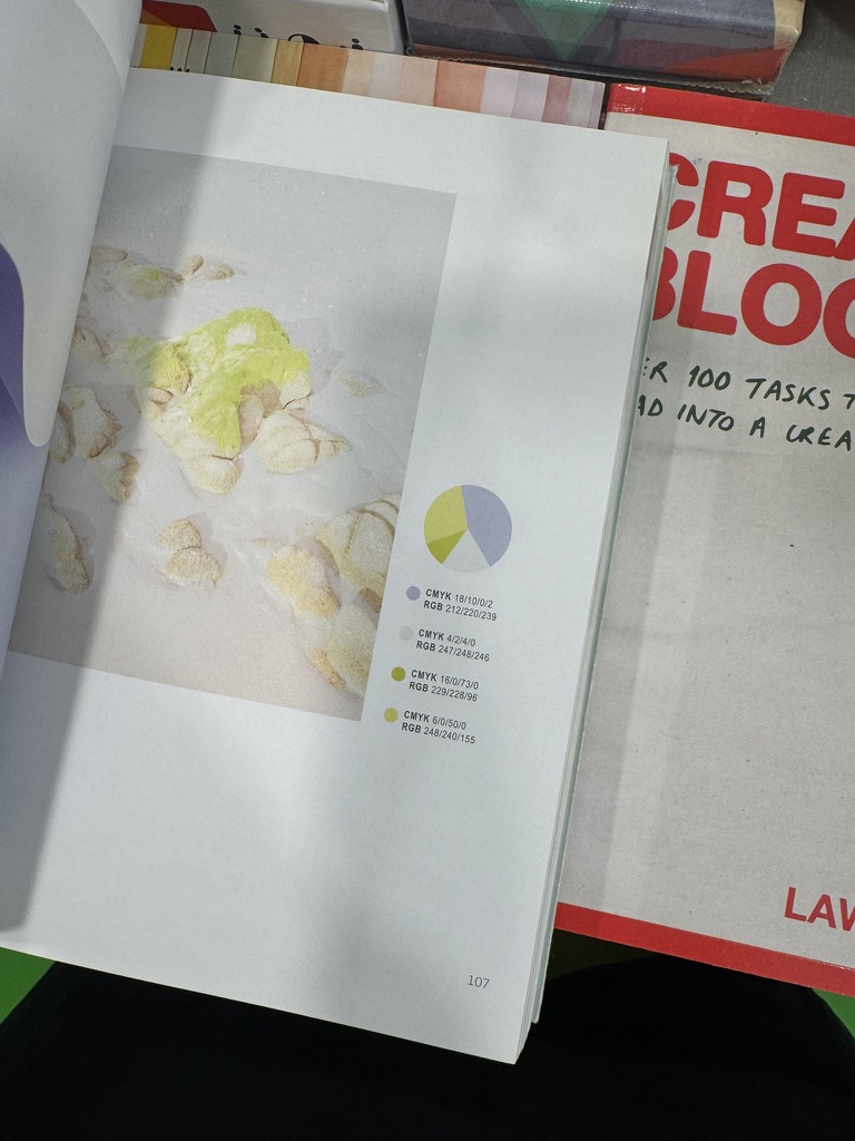 An open design book showing a photograph and its palette: lavender, off-white, and two pale yellows.